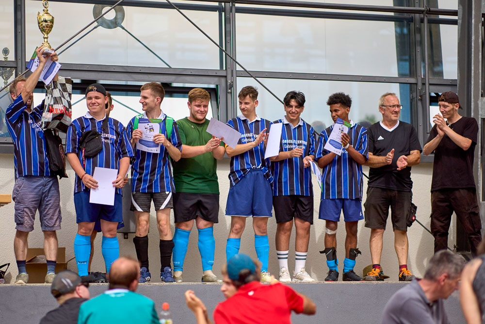 Verschiedene Junge Männer einer Fussballmannschaft stehen nebeneinander und applaudieren zum Pokalsieg